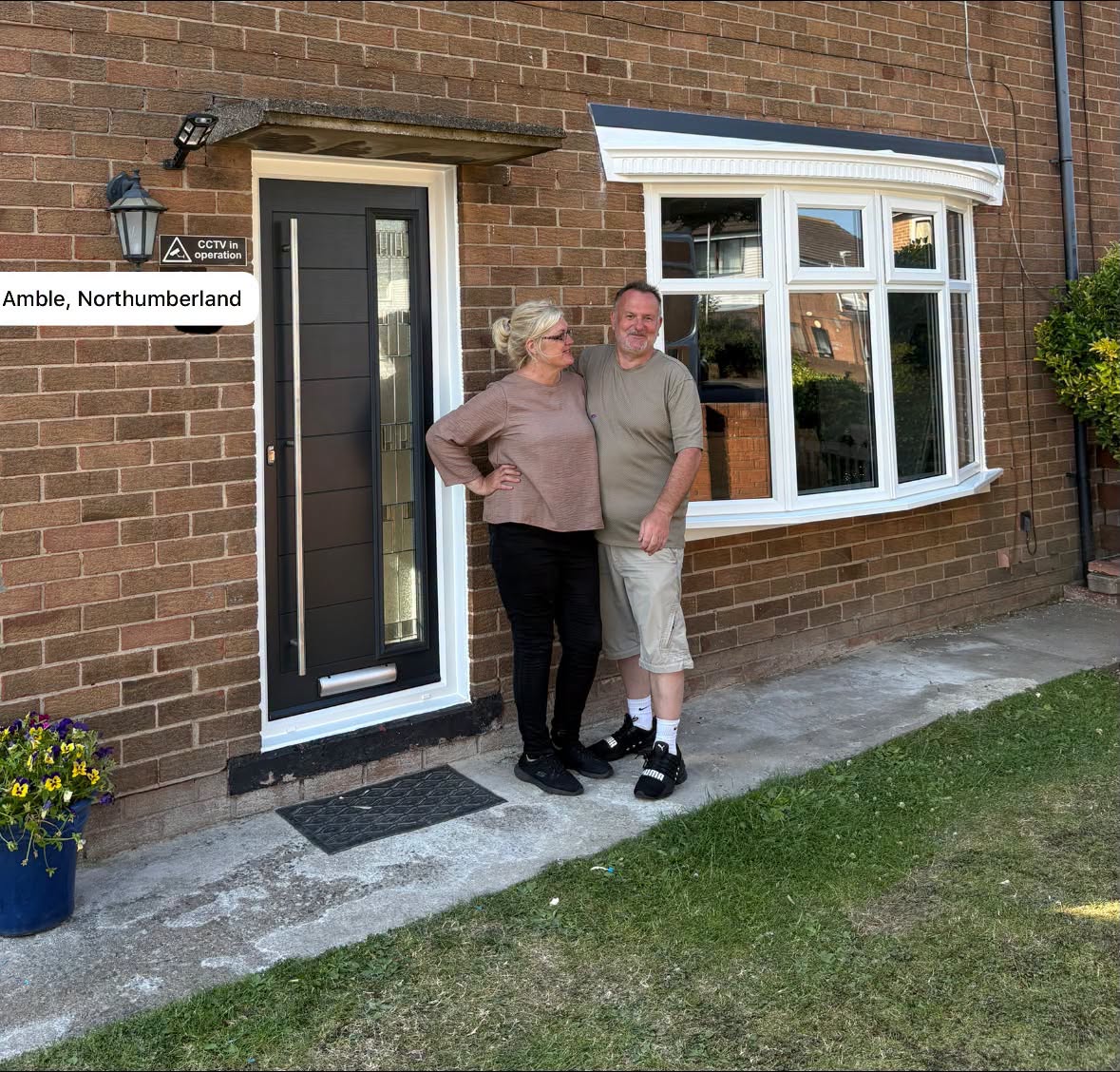 Window Warriors customers beside their newly fitted composite front door and bow window in Amble, Northumberland